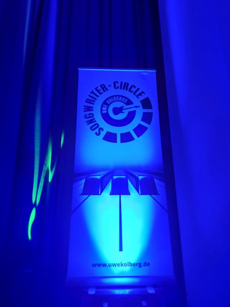 Rollup mit dem Logo von Uwe Kolbergs Songwriter-Circle im Saal des Haus Schwärzetal