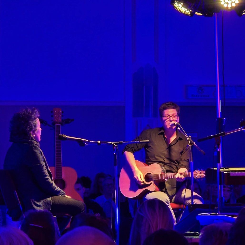 Songwriter mit Akustikgitarre im blauen Bühnenlicht beim Songwriter-Circle in Eberswalde